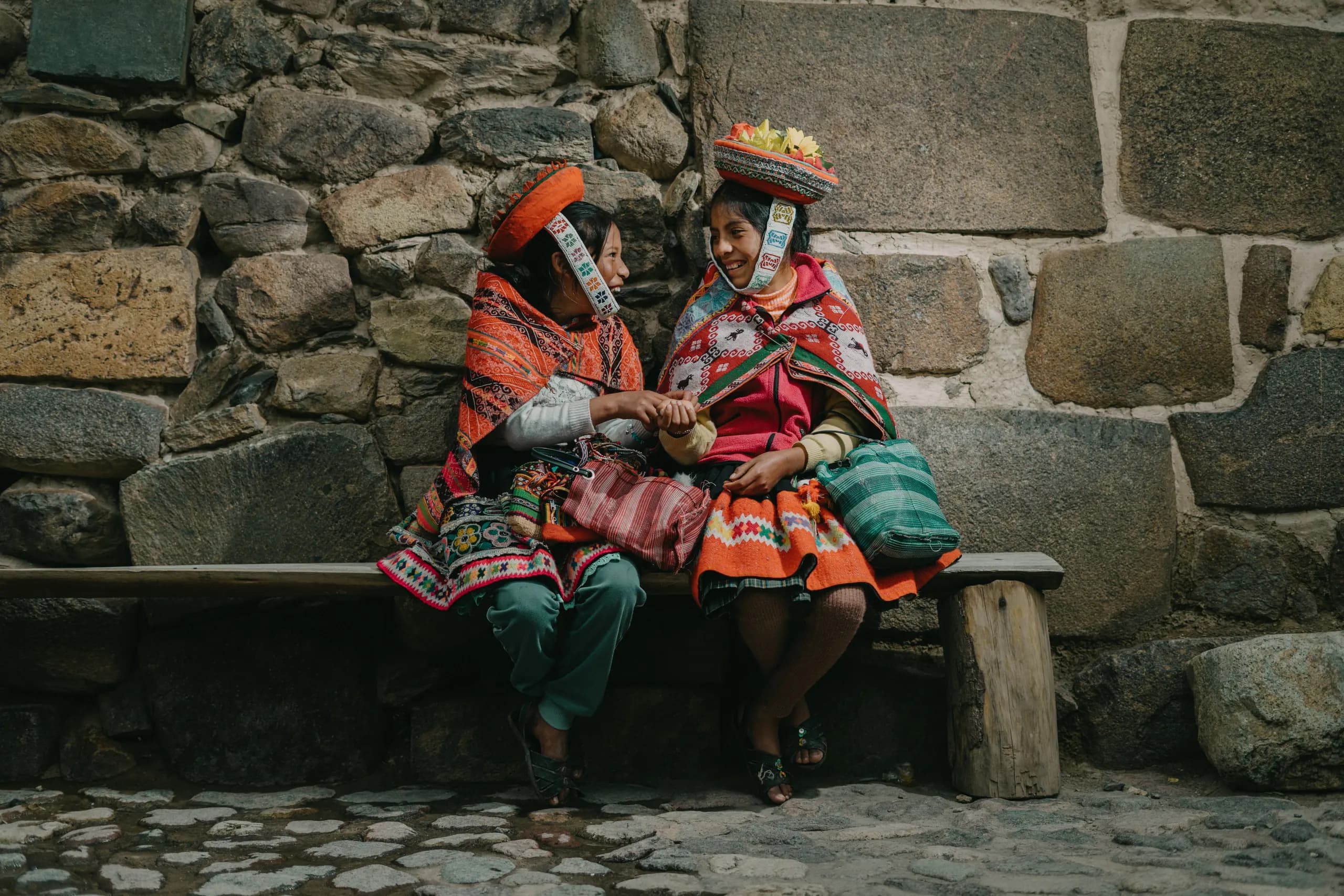 Women in traditional clothing beside a stone wall