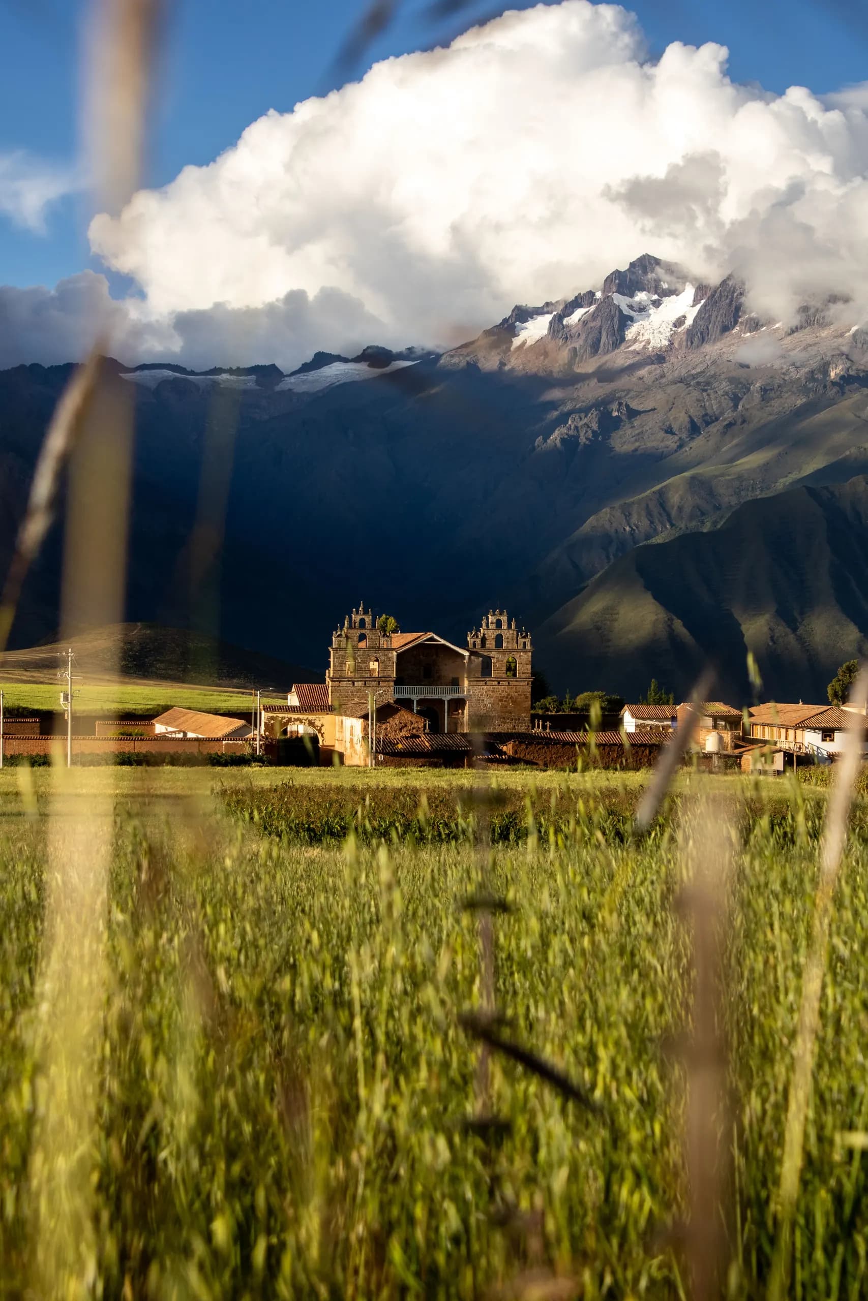 Stone ruins in a meadow with snow-covered mountains behind