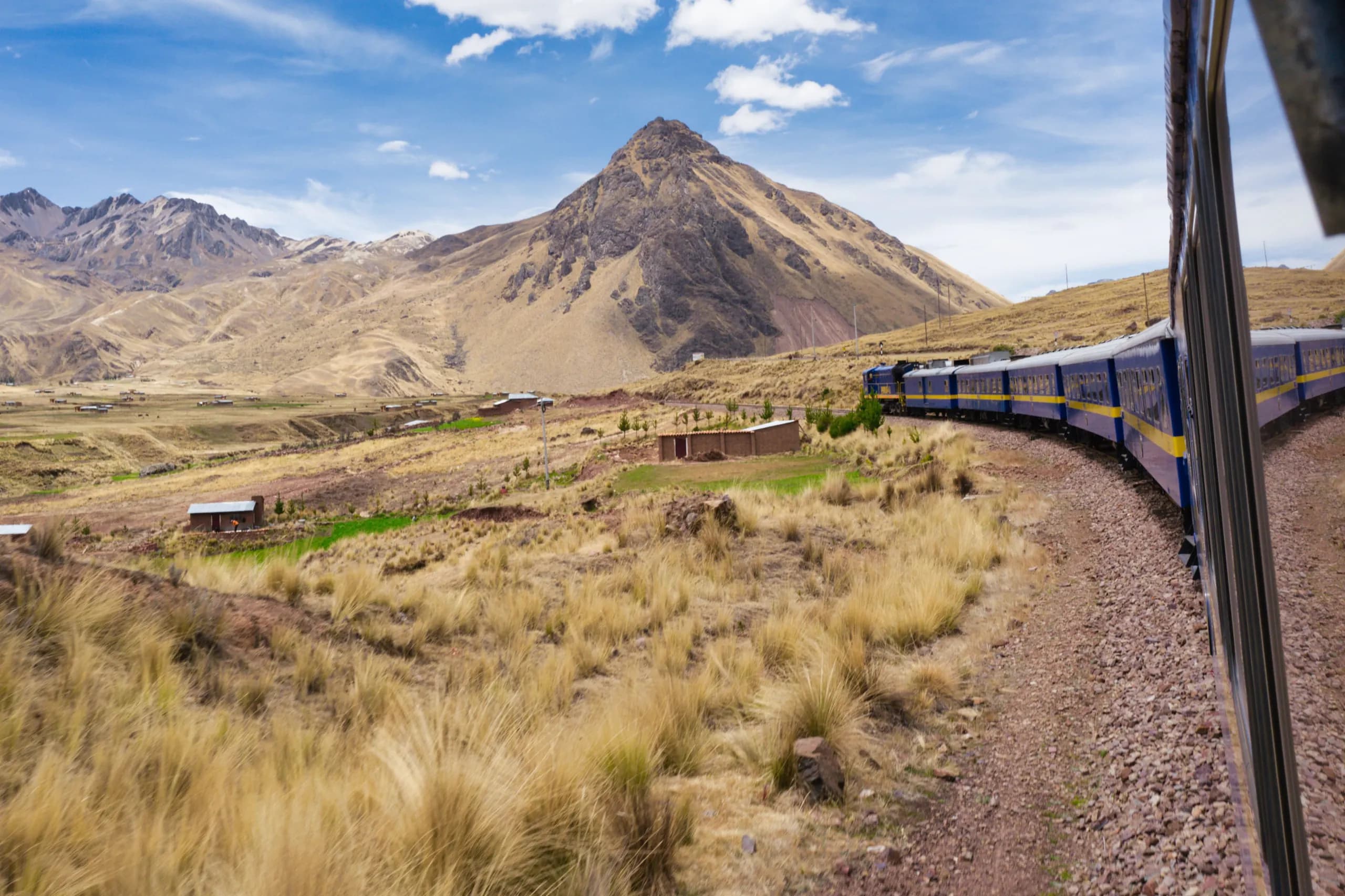 Train crossing a meadow among mountains