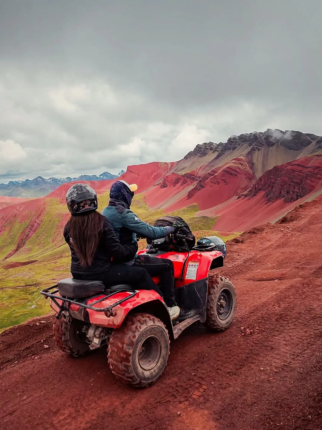 Travellers on a quad bike beside the mountains of Vinicunca
