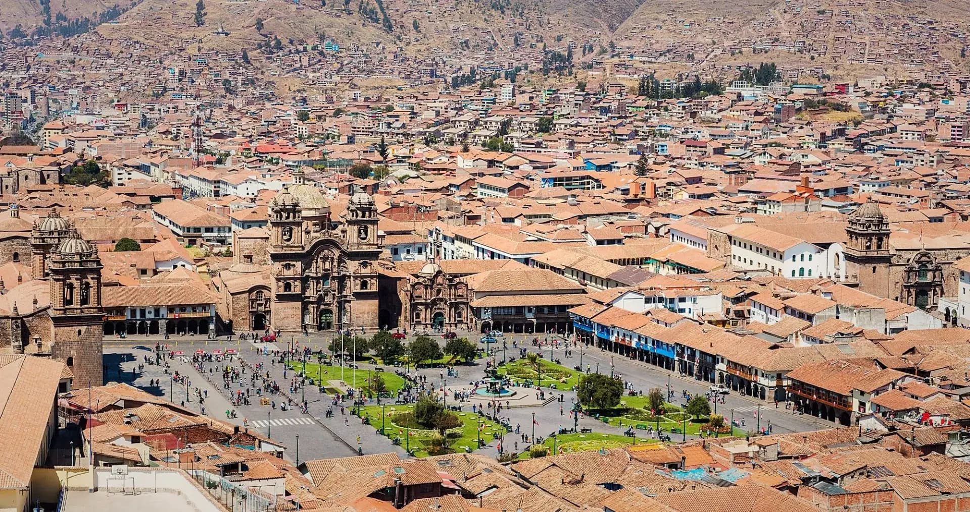Panoramic view of the rooftops and streets of Cusco among mountains